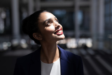 Pretty mixed-race businesswoman looking up in modern office