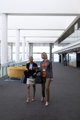 Multi-ethnic businesswomen interacting with each other while walking in office