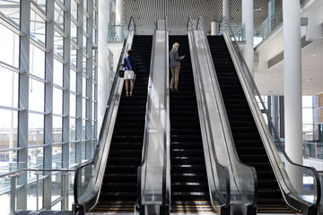 Multi-ethnic businesswomen using escalator in modern office 
