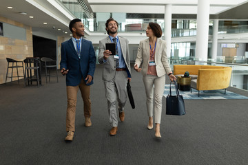 Multi-ethnic business people interacting with each other while walking on office floor - Powered by Adobe
