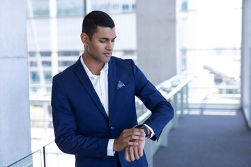 Young mixed-race businessman using smartwatch in modern office