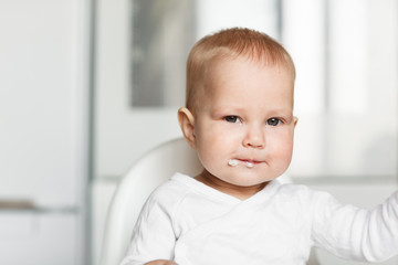 Feeding of cute baby with a spoon in the kitchen