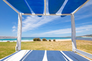 beautiful scenery of Bolonia Beach framed from a wooden Balinese bed with blue surf boards, in Tarifa (Cadiz, Andalusia, Spain)