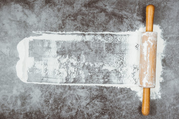 Baking flat lay with rolling pin, flour on gray background. Bake menu, recipe, homemade pastry concept. Top view, with copy space for your text.