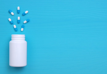 Pills, tablets and bottle on blue background.