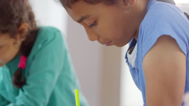 Handheld shot of cute schoolgirls drawing together during recess in school