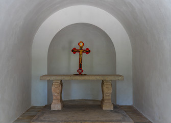 A cross with a crucifix stands on a table in an old chapel in the catholic Christian...