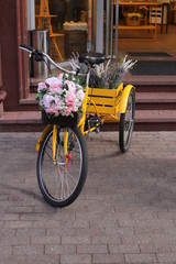 Fototapeta na wymiar vintage yellow bicycle with flowers on the street