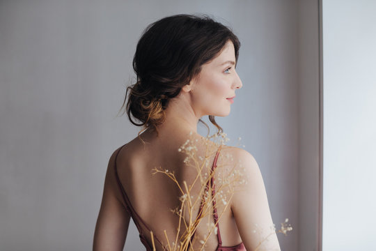 Back view of beautiful tender young woman in silky nightgown.
