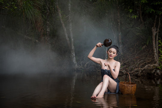 The  sexy women white skin are bathing in a stream in a forest surrounded by trees. She enjoys rural life.