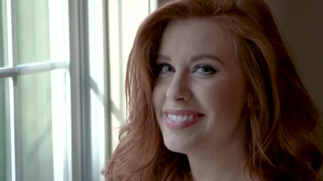 Beautiful red headed woman smiling and looking at camera