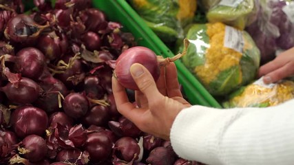 Close-up of a man chooses red onions in a supermarket. The family buys food and vegetables at the grocery store. Slow motion.