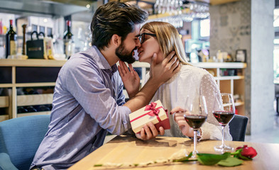 Birthday present for a girlfriend. Romantic couple sitting in the cafe and drinking red wine. Dating, love, relationships