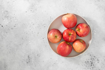Apples in a white plate on a light gray background