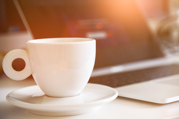 Cup of coffee and laptop for business. Selective focus on coffee. Sun effect style picture