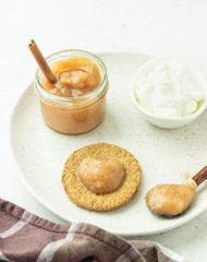 Thin crispy wholegrain crackers with natural yogurt and jam on a grey plate. Simple breakfast or snack. 