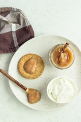 Thin crispy wholegrain crackers with natural yogurt and jam on a grey plate. Simple breakfast or snack. 