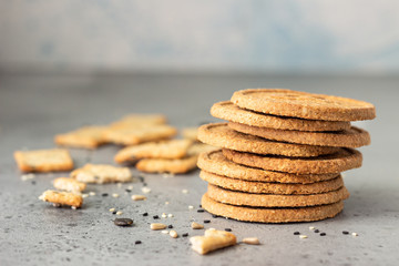 Thin crispy wholegrain crackers with seeds on grey concrete background. 