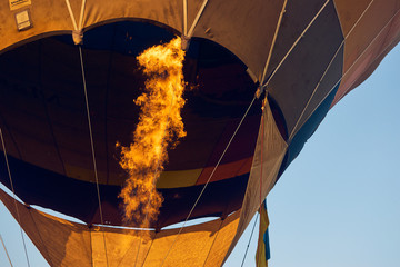 Heated air in a balloon using a burner fire.