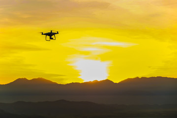 Fototapeta na wymiar Drone quadcopter flying on mountain sunset silhouette scene