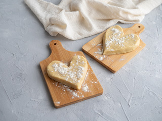 Two heart-shaped buns on small wooden planks on a gray concrete background with a cloth napkin.
