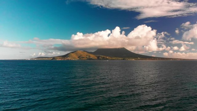 Nevis Peak volcano covered in thick clouds beyond teal Caribbean Sea
