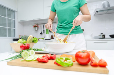 Delicious. young pretty woman in green shirt standing and preparing the vegetables salad in bowl for good healthy in modern kitchen at home, healthy lifestyle, cooking, healthy food,  dieting concept