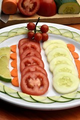 tomato salad, cucumber, carrot, accompanied with a lemon, placed on a white plate on a wooden table and with background the inputs used