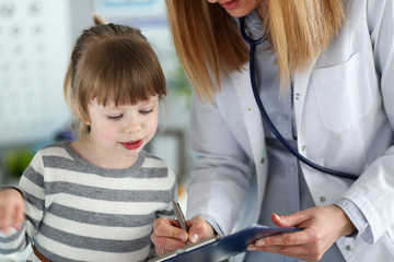 Portrait of little girl on meeting with physician. Cheerful kid wearing casual striped dress to visiting family doc. Health care and prevention concept. Blurred background