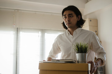 Losing job. stressed asian young employee business man leaving the office with his personal stuff carton box, financial crisis, unemployed, last day at work, fired from job and lay off concept