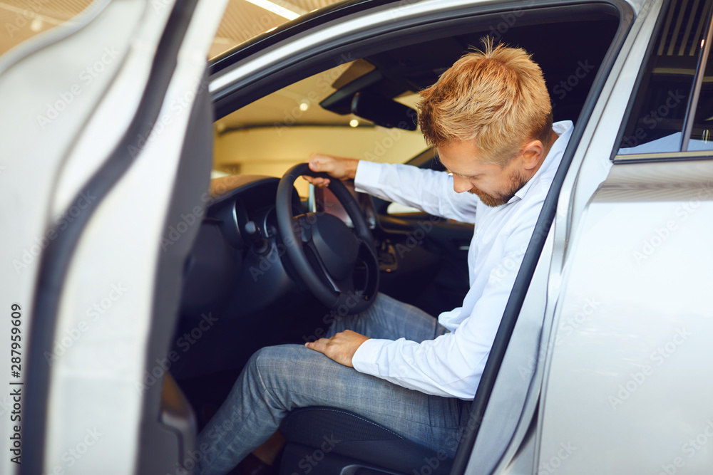 Wall mural auto business. male buyer look at a new car.