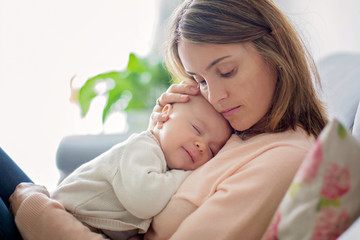 Young mother, holding tenderly her newborn baby boy