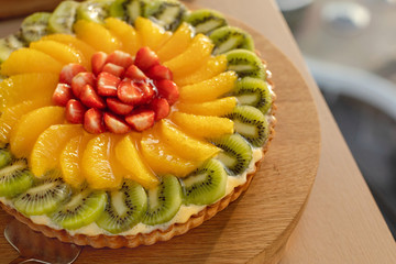 Tempting shortcrust pastry with cream and fresh sugary fruits and berries served on wooden tray