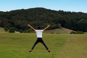 mann springt auf der wiese hoch unter blauem himmel bewegung freizeit