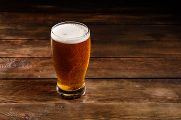 Glass of light beer on a dark pub. Glass beer on wood background with copy space