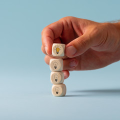 Hand stacking dices with light bulb symbol on them