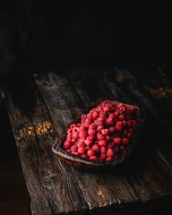 ripe raspberries in wooden bowl on brown wooden table