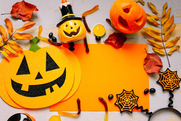Halloween decorations on a gray background. Concept of Halloween. Flat position, top view, copy space. Pumpkin, candy, mask, piece of paper.