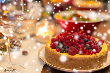 christmas dinner and eating concept - close up of berry cake and other food on table at home over snow