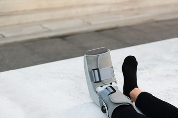 A Asian girl is wearing a ankle support boot after surgery.