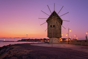 Fototapeta na wymiar Old Windmill by an isthmus to old Nessebar Bulgaria. Ancient wooden windmill on the sea coast, Nessebar