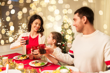 holidays, family and celebration concept - happy mother, father and little daughter having christmas dinner at home