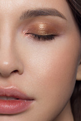Fototapeta premium Close-up half face of sexy european young woman model with classic glamour make-up and nude lipstick. Dark long hairstyle, christmas makeup, dark eyeshadows, natural pink lips with gloss