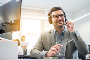 Customer service operator man with headset listening to a client with attention while working in...
