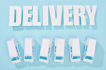 delivery inscription with shadows near mini vans on blue background