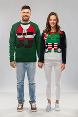 christmas, people and holidays concept - happy couple at ugly sweater party