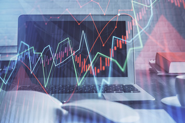 Stock market graph on background with desk and personal computer. Multi exposure. Concept of financial analysis.