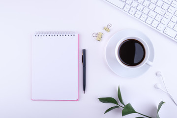 Office desk with blank notepad, laptop computer, cup of coffee and supplies. Top view with copy space, flat lay