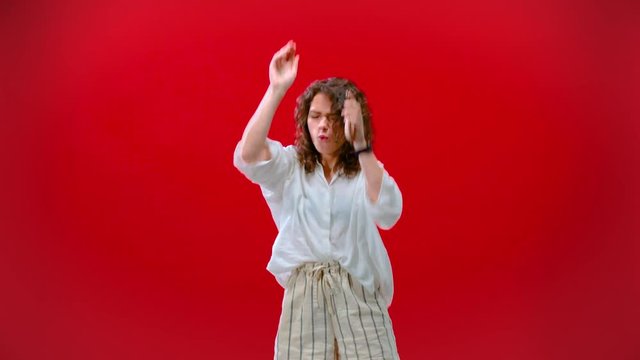 Girl dancing with an iPhone 11pro in hand on a red background