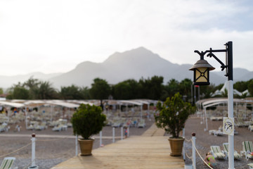 Idyllic view of the wooden pier in the sea with beach and mountain scenery background. Warning sign...